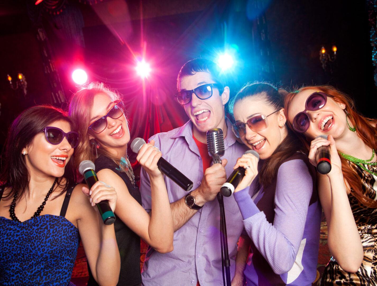 group of young people singing into  microphone at  party. karaoke